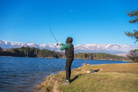 A male fisherman on the lake is standing in the water and fishing for a fishing rod. Fishing hobby...