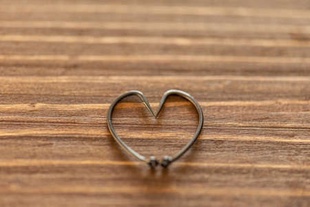 Fish hook heart on a wooden background.の写真素材