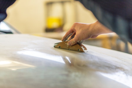 Grinder in the hands of a man who sharpen a car varnish in the car shop.の写真素材