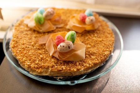 Easter cake with yellow mirror glaze, chocolate, spring flowers, quail eggs on dark stone...