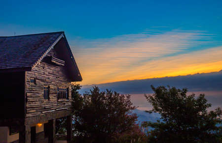 Sunrise beyond wooden hut in mountain terrain.の写真素材