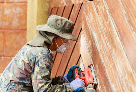 A worker use electric sander on wooden doorの写真素材