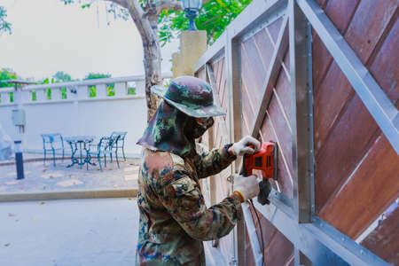 A worker use electric sander on wooden doorの写真素材