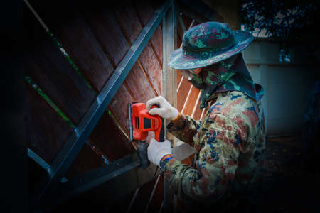 A worker use electric sander on wooden doorの写真素材