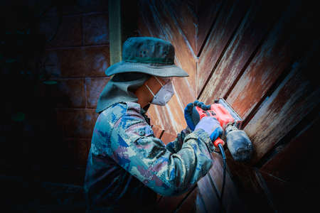 A worker use electric sander on wooden doorの写真素材