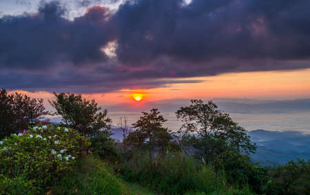 Sunrise at mountain terrain in a sea of mist, on cloudy skyの写真素材