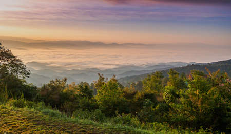Sunrise at mountain terrain in a sea of mist, on cloudy sky. Beautiful panoramic view of highland.の写真素材