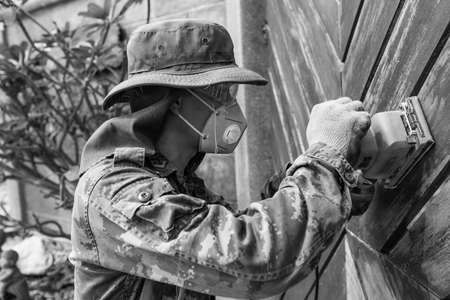 A worker use electric sander on wooden door