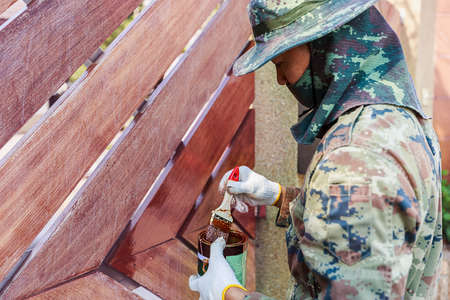 Painter man at work, painting a wooden door with brush, home improvement and renovation concept.の写真素材