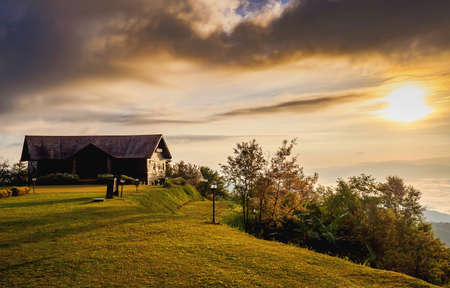Sunrise beyond wooden hut in mountain terrain.の写真素材
