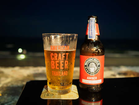 HuaHin, Thailand - April 9, 2017: Bottle of Woodchuck Amber beer and glass of American Craft Beer on the table at HuaHin Beach during night time.のeditorial素材