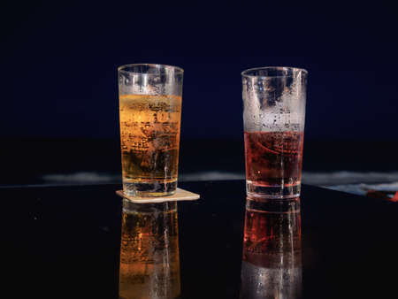 Glass of beer on the table at the beach during night time.の写真素材