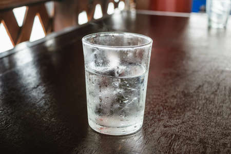 A glass of water with ice, on the wooden table.の写真素材