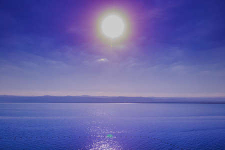 Beautiful sunset at Dead Sea coastline in Jordan, glittering of sunshine in water, blue sky background.の写真素材