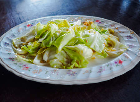 Stir fried cabbage with fish sauce, famous Thai traditional food, on the wood table.