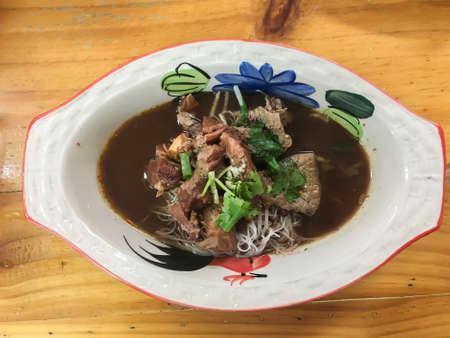 Thai style rice noodle soup with stewed beef and herbs, served in boat bowl and chopsticks.の写真素材