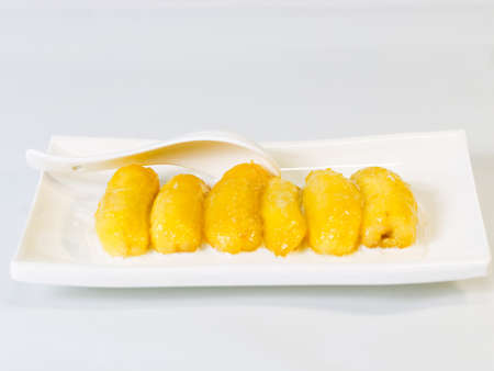 Preserved banana in syrup, Thai style, served on a white plate and spoon.の写真素材