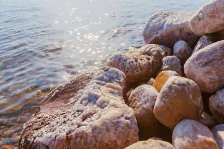 Close up of natural salt crystals, texture of salt. Small waves touching against salted rock shore...