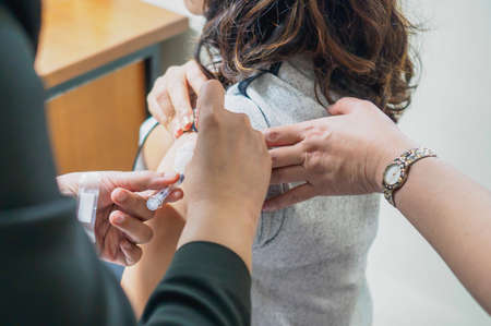 Close up of patient getting a vaccination in the hospital. The injection are treated by a nurse on...