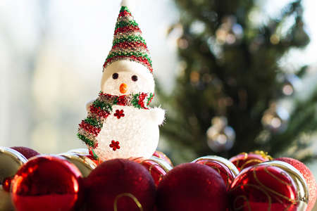 Selective focus of cute little snow man sitting on Christmas decorations and holiday decor with Christmas tree behindの写真素材