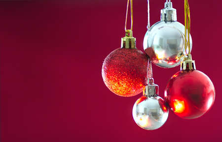Red and silver Baubles hanging against solid Background