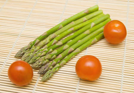 Aspargus stems and tamatos on bamboo substrate の写真素材