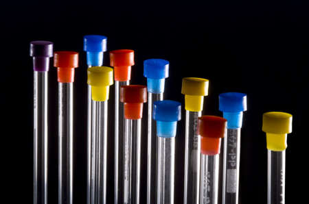test tubes with multicolored tops back lit on blackの写真素材