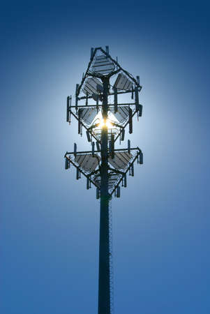 Cell tower back lit by sun on a clear blue skyの写真素材