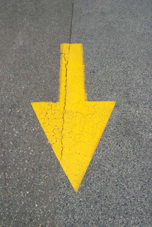Yellow painted arrow on asphalt street