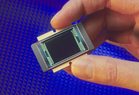 Fingers holding a microprocessor chip on blue backgroundの写真素材