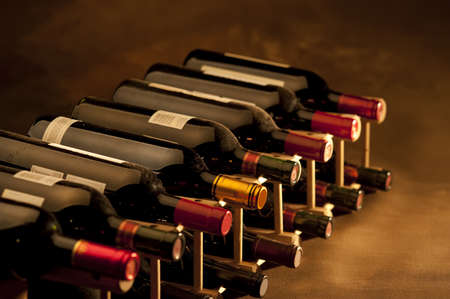 Red wine bottles stacked in rack on warm background