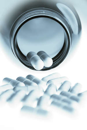 Pills/capsules pouring out of medicine bottle in bluesの写真素材