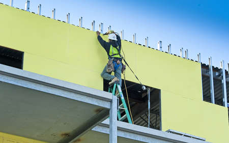 Construction worker screwing outdoor sheet rock into new buildingの写真素材