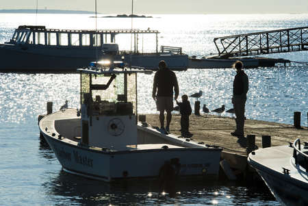 Family strolling on boat dock in early morning lightの写真素材