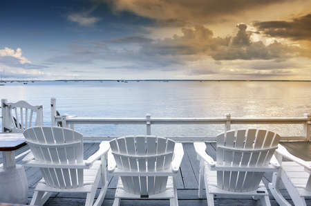 beach chairs overlooking tranquil ocean at sunset on old cape codの写真素材