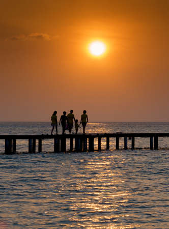 Silhouette of family walking over a bridge at sunsetの写真素材