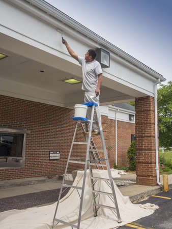 Hispanic man painting soffit of a buildingの写真素材