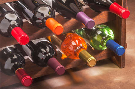 wine bottles stacked in a rack with colorful foil necksの写真素材