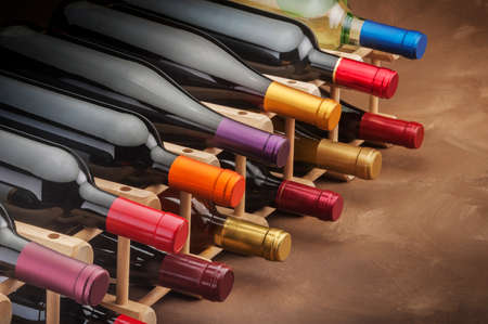 wine bottles stacked in a rack with colorful foil necksの写真素材