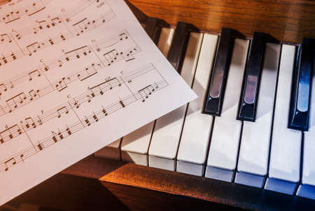 Piano keys and sheet music in cool blue and warm orangeの写真素材