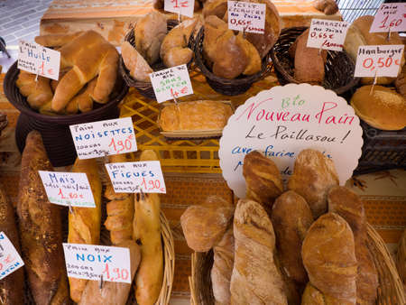 Artisan French breads in local outdoor market in France with description and prices in euros.のeditorial素材