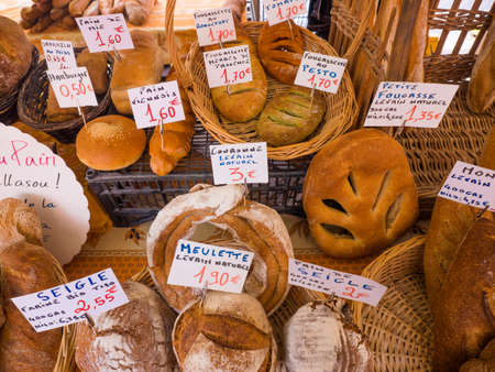 Artisan French breads in local outdoor market in France with description and prices in euros.のeditorial素材