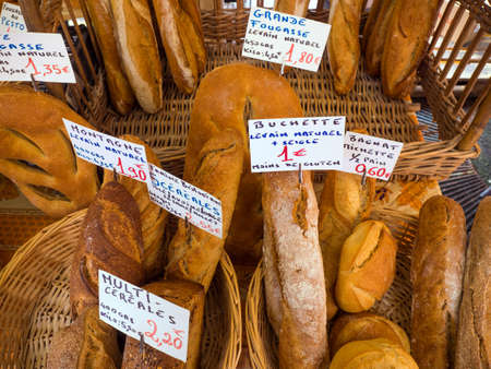 Artisan French breads in local outdoor market in France with description and prices in euros.のeditorial素材