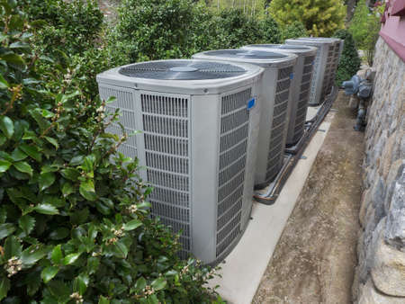 Air conditioning and heating units for a big residential house hidden by hollyの写真素材