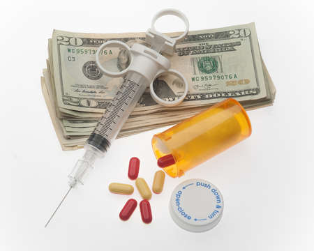 Cost of drug addiction concept with needle, money and drugsの写真素材