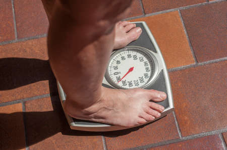 A severely overweight person weighing herself or himself on a bathroom scaleの写真素材
