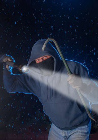 Burglar prowling on a rainy night looking to break into a houseの写真素材