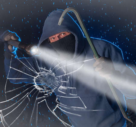 Burglar prowling on a rainy night looking to break into a houseの写真素材
