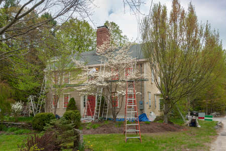 man with paintbrush painting wooden house exteriorの写真素材