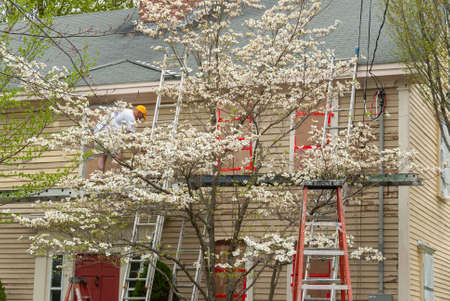 man with paintbrush painting wooden house exteriorの写真素材